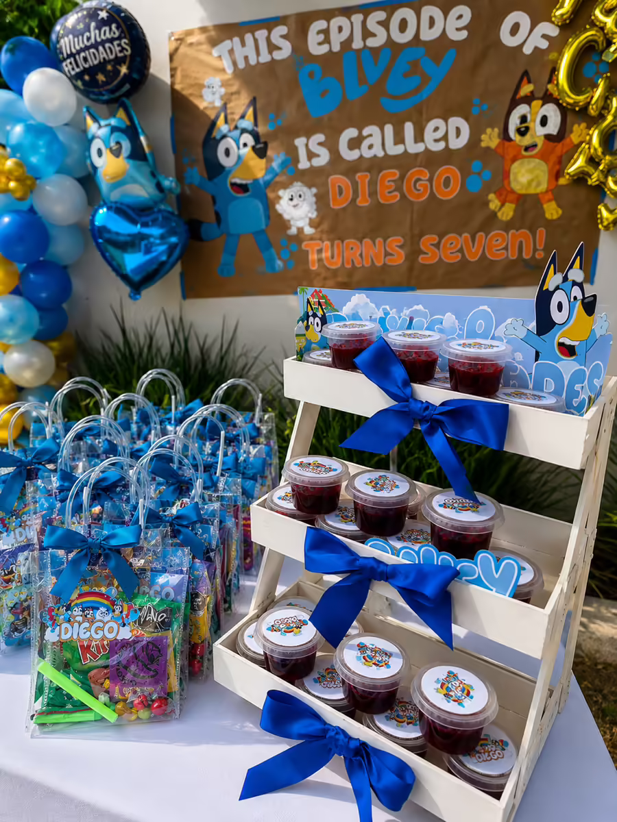 Estacion de souvenirs en candy bar Bluey con bolos azules personalizados, presentacion organizada en escalera y liston coordinado para cumpleanos infantil en CDMX