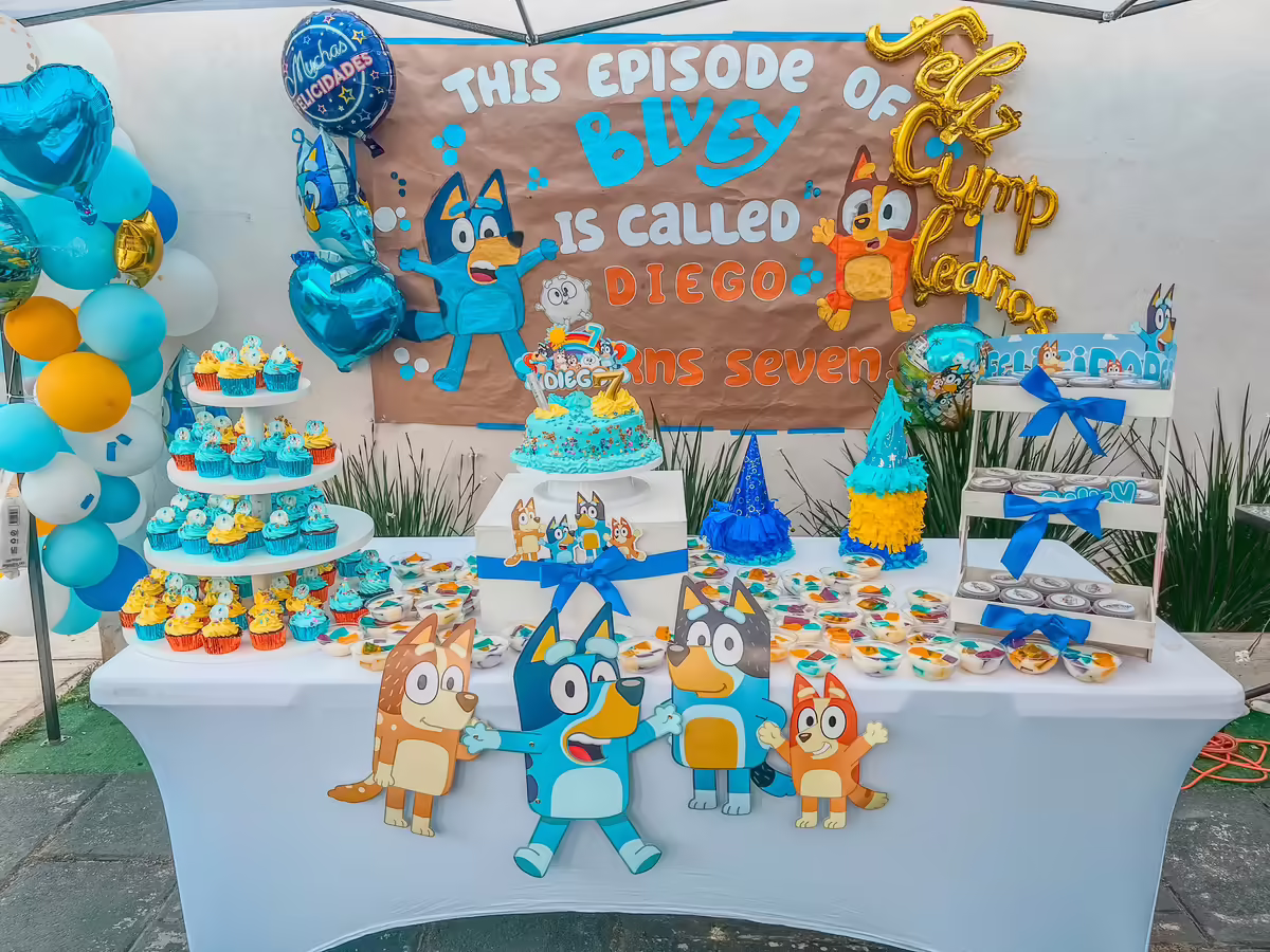 Mesa de dulces tematica Bluey completa con backdrop, torre de cupcakes, gelatinas, pastel principal Bluey y bolos personalizados para cumpleanos infantil en CDMX en momento pico del evento