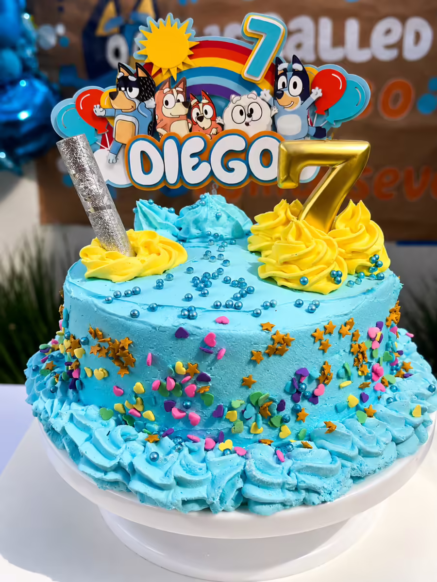 Pastel de cumpleanos Bluey con decoracion tematica completa, sprinkles coloridos, figura Diego 7 anos personalizada en fondant azul y velas tematicas para corte oficial