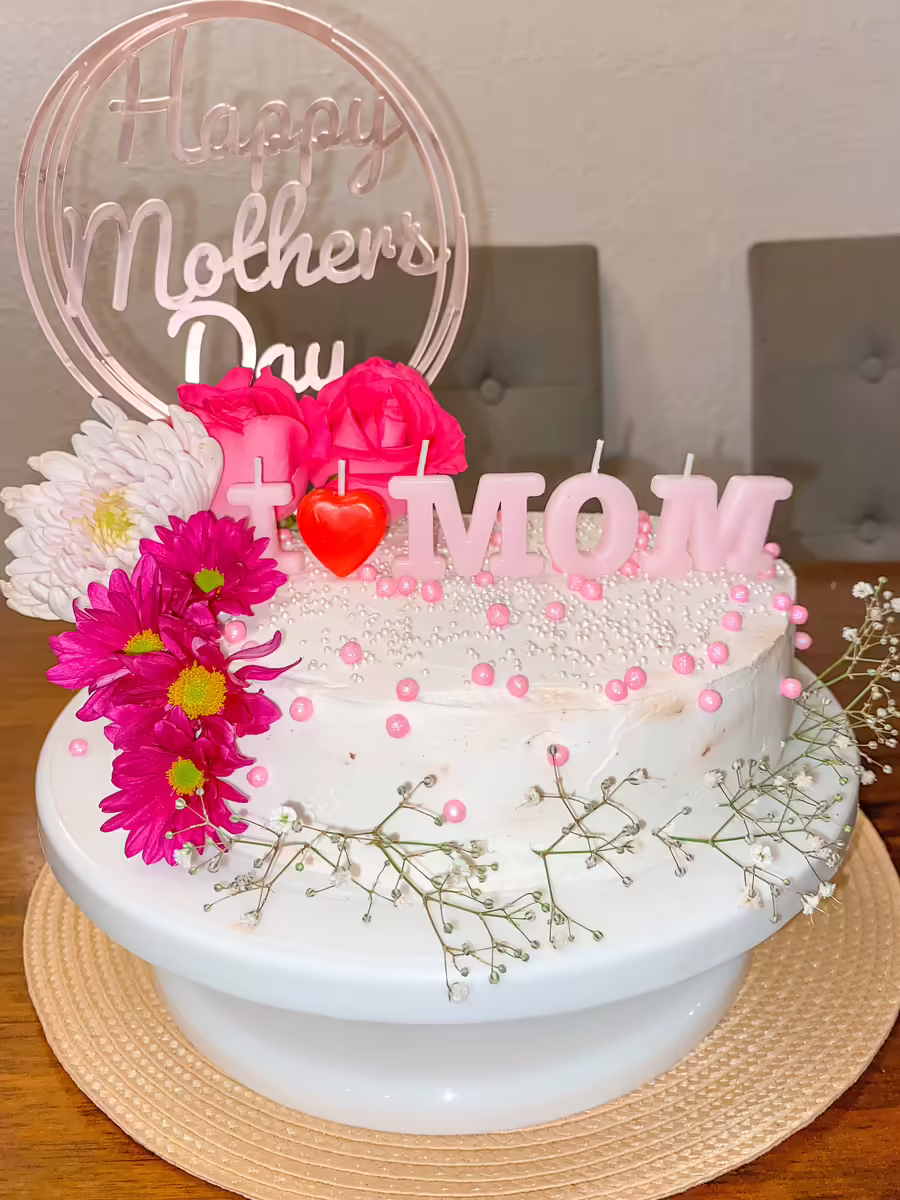 Pastel para Dia de las Madres con flores fucsia naturales frescas, decoracion elegante con la palabra MOM en acrilico transparente, perlas comestibles y velas tematicas para celebracion sofisticada en CDMX