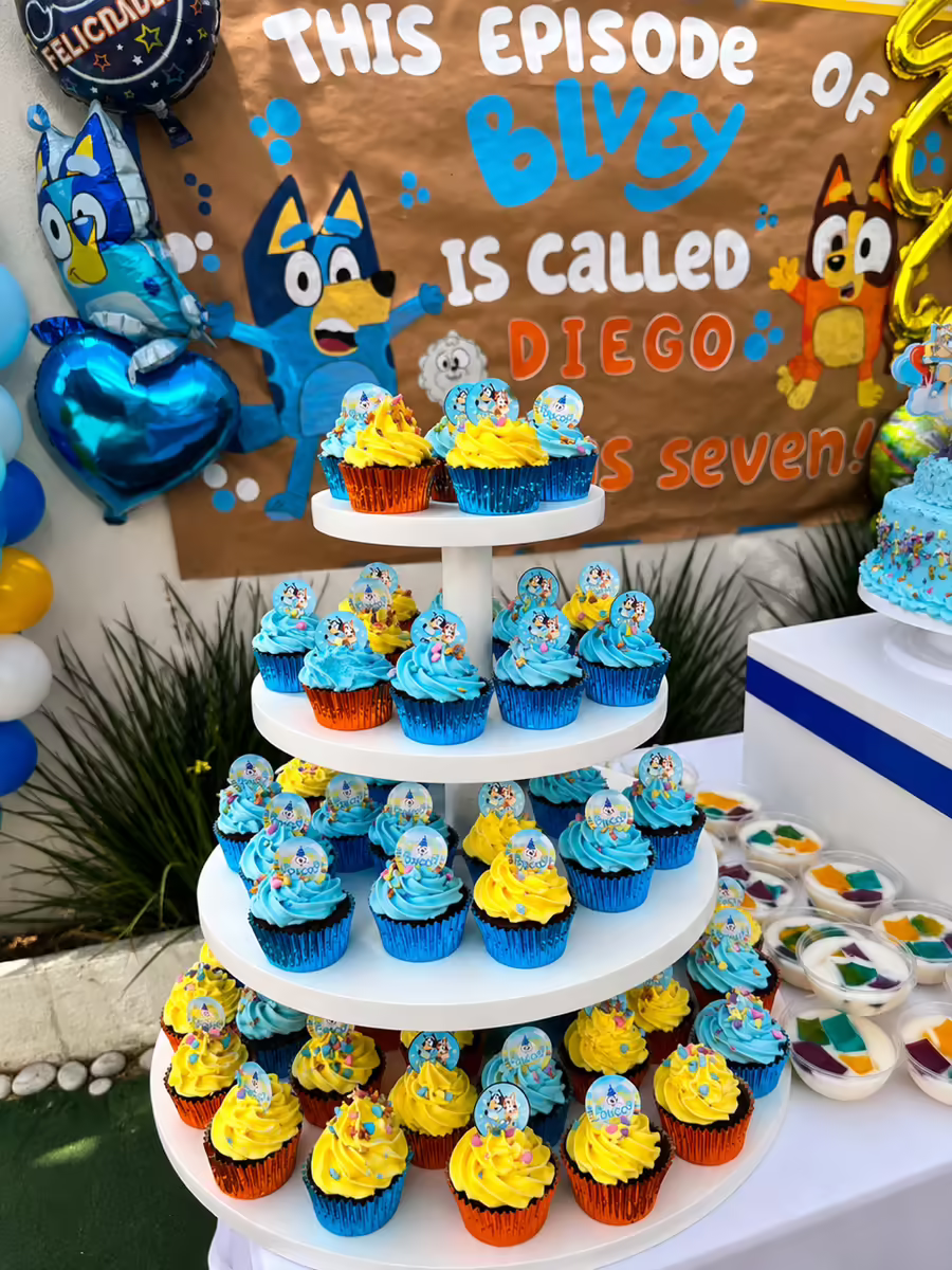 Torre de cupcakes Bluey en charola de tres pisos con cupcakes azules y amarillos coordinados, paletas tematicas y figuras Bluey Bingo personalizadas para cumpleanos infantil